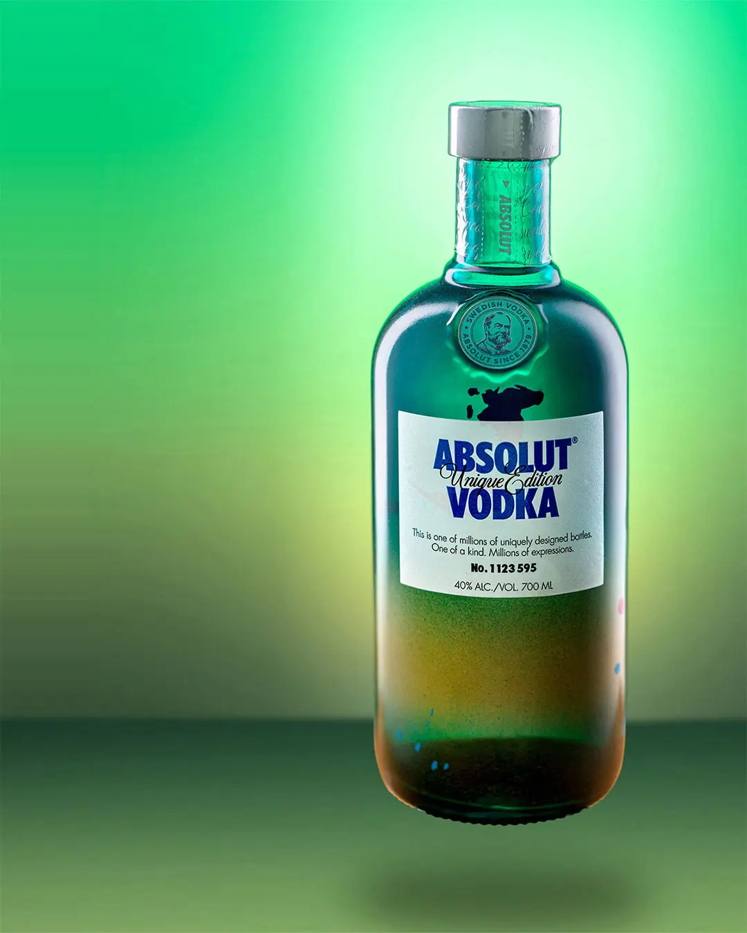 Produktfotografie Absolut Unique Edition Vodka in einer grün-blauen Farbflasche auf einem leuchtend grünen Hintergrund.