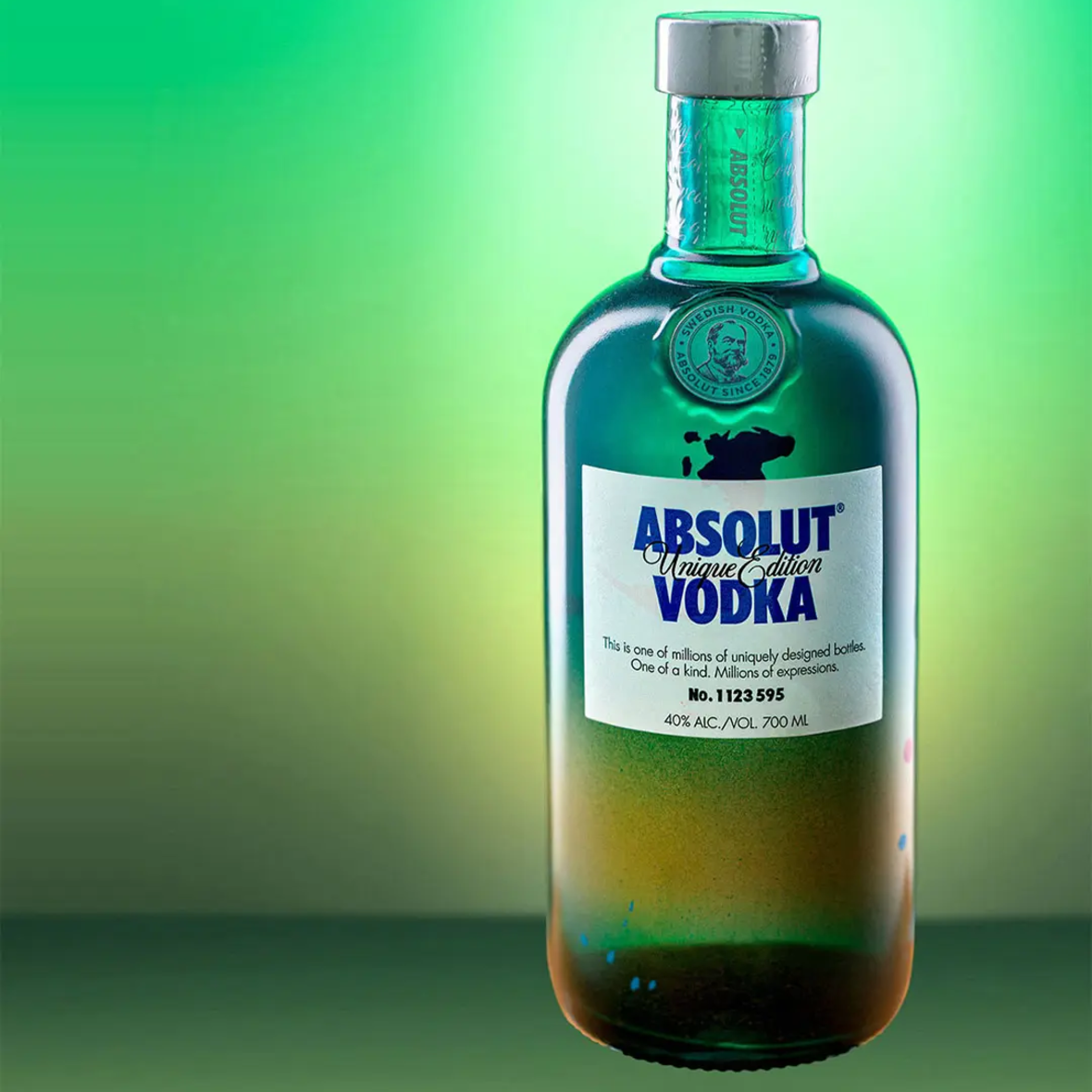 Produktfotografie Absolut Unique Edition Vodka in einer grün-blauen Farbflasche auf einem leuchtend grünen Hintergrund.